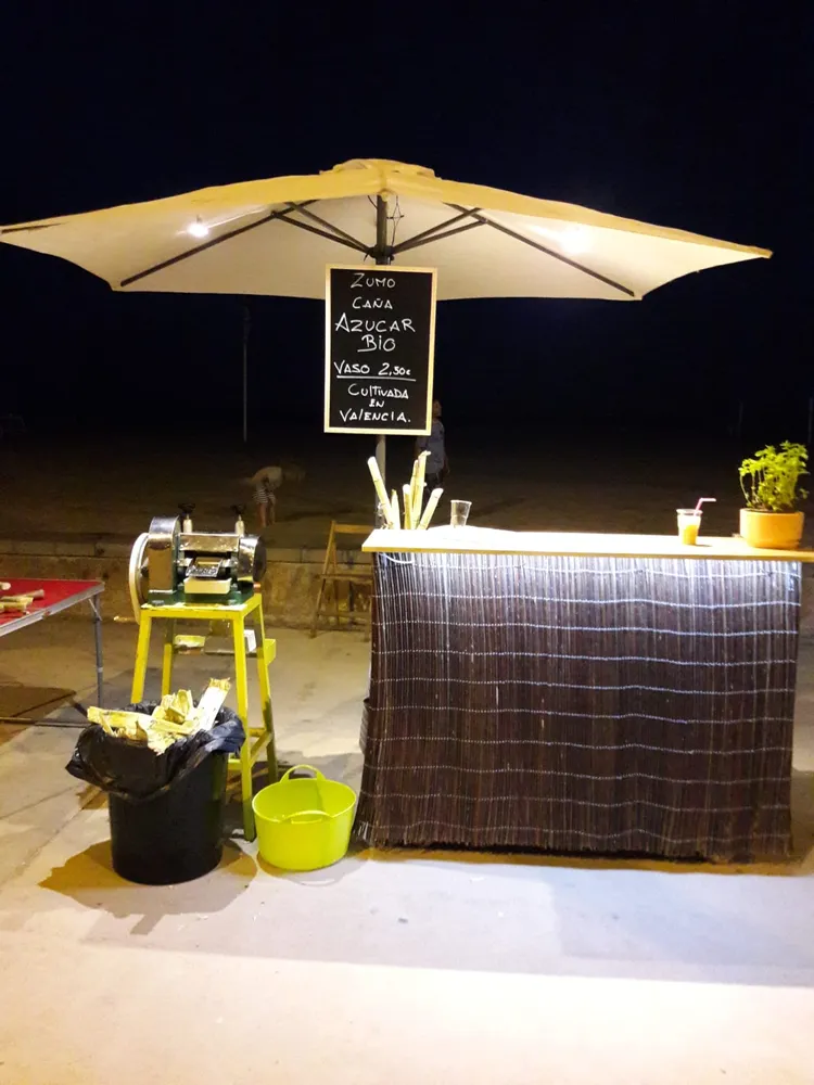 La barra del Cañabar de noche, con el exprimidor de caña y la pizarra de zumo de caña de azúcar bio